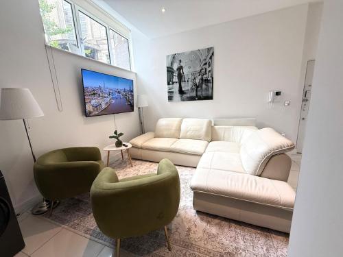 a living room with a white couch and two chairs at Kings Cross St Pancras One Bedroom Flat in London