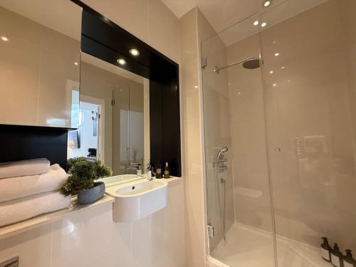a bathroom with a shower and a sink and a mirror at Kings Cross St Pancras One Bedroom Flat in London