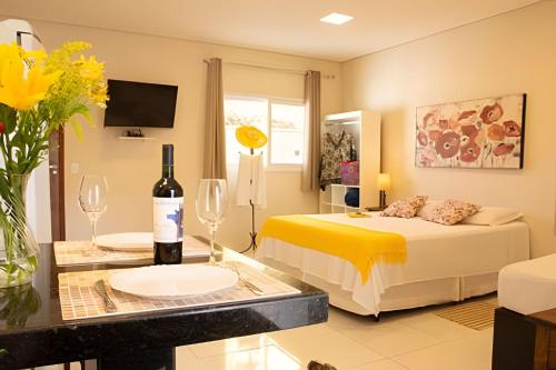 a bedroom with a bed and a table with a bottle of wine at Flats Premium Jabaquara in Paraty