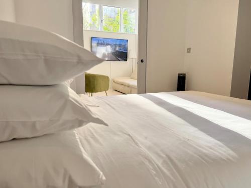 a white bed with white pillows in a bedroom at Kings Cross St Pancras One Bedroom Flat in London