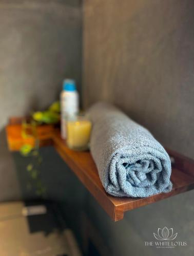 une serviette posée sur une étagère en bois dans une salle de bain dans l'établissement White Lotus Apartments, à Dankotuwa
