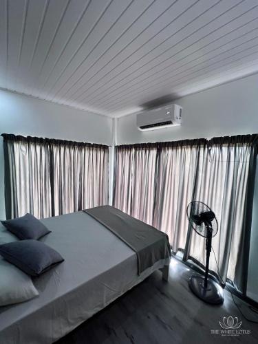 - une chambre avec un lit avec des rideaux et un ventilateur dans l'établissement White Lotus Apartments, à Dankotuwa