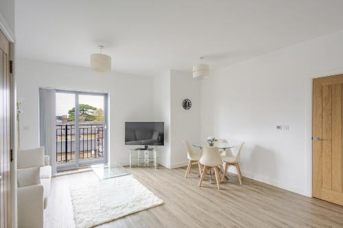 a white living room with a table and a tv at Luxury Apartment in Chelmsford City, Free WiFi & Free Parking - The Signal Yard by Stays Accommodation - Long Stays Welcome in Chelmsford