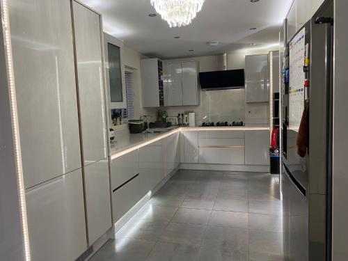 una cocina blanca con armarios blancos y una lámpara de araña en Moore Place, en Houghton Regis