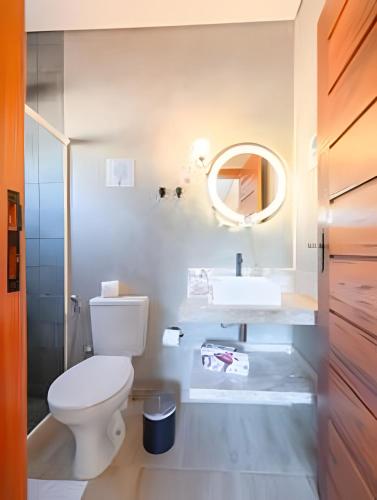 a bathroom with a white toilet and a sink at Lofts Corujinha Paraty in Paraty