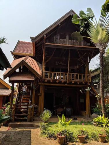 a wooden house with a balcony and a palm tree at Thai Tom s GuestHouse in Chiang Mai