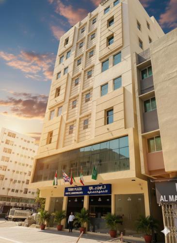 a large building with flags in front of it at Town Plaza Hotel Apartments Ras Al Khaimah in Ras al Khaimah