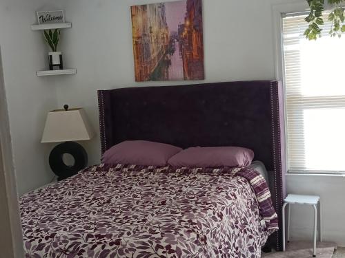 a bed with purple pillows in a white bedroom at Zen Gem Near Downtown Detroit and Grosse Pointe in Detroit