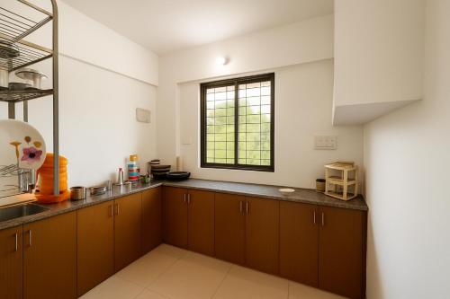 a kitchen with brown cabinets and a window at New Spacious 2BHK apartments in Tirupati Near Railway Station with fully equipped kitchen, AC bedrooms, Washing Machine, 24 hours water, caretaker service, and ample space for car parking & ideal for families and pilgrims in Tirupati