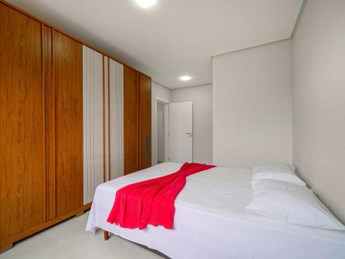 a bedroom with a white bed with a red blanket on it at Apto c/ churrasqueira a 700m da praia MU3731 in Gravata