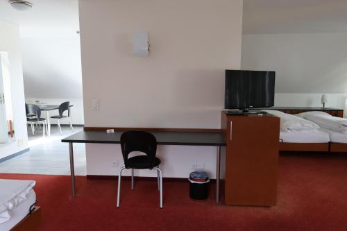 a room with a desk with a television and a bed at Hotel Urs und Viktor in Bettlach