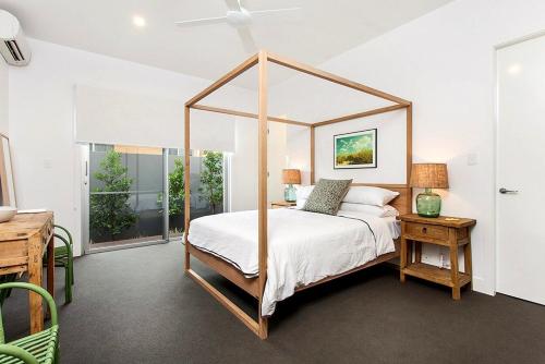 a bedroom with a canopy bed and a table at Stonecutters 2 in Byron Bay