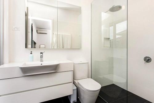 a white bathroom with a sink and a toilet at Stonecutters 2 in Byron Bay