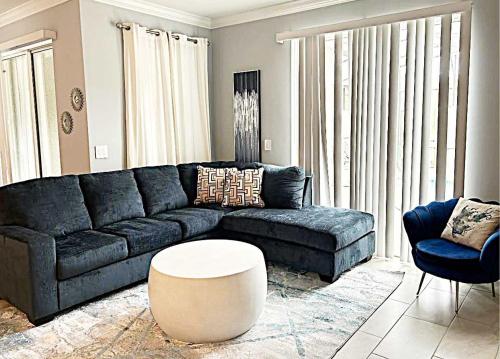 a living room with a blue couch and a table at Gorgeous Condo Close to Disney w Private Pool BBQ - Themed Bedrooms Walk To Clubhouse in Kissimmee