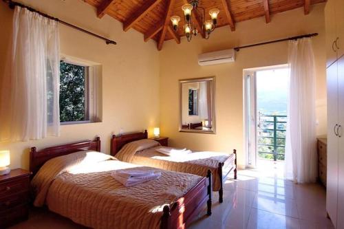 two beds in a room with a large window at Villa Aliona in Mavráta