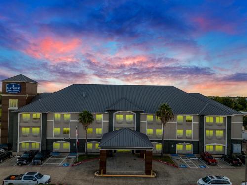 an exterior view of a hotel with a parking lot at Platinum Inn & Suites Webster in Webster