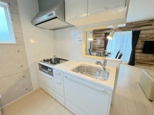 a white kitchen with a sink and a stove at Grandioso OKINAWA VILLA ONNA 5A - Vacation STAY 97835 in Meta