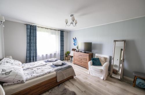 a bedroom with a bed and a mirror and a chair at Apartament w lesie in Lipnica
