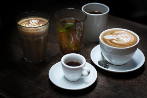 three cups of coffee on a wooden table with drinks at Apartments by Brøchner Hotels in Copenhagen