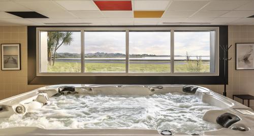 une grande baignoire dans une pièce avec une fenêtre dans l'établissement Best Western Côte des Sables Plouescat, à Plouescat