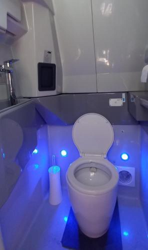 a bathroom with a white toilet with blue lights at Unique et Insolite Bus Iliade in Bourg