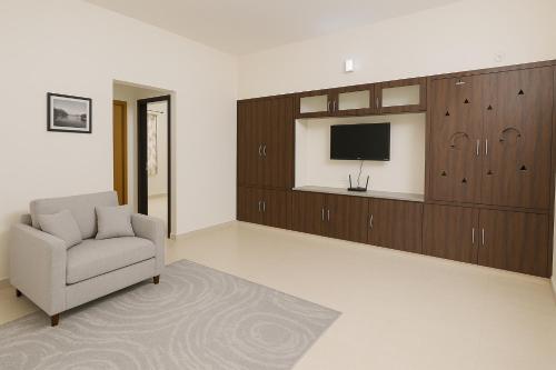 a living room with a chair and a tv at Bhakti Bliss Homestay - New Luxury 2bhk apartment in Tirupati with Kitchen and car parking in Tirupati