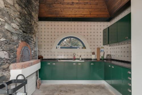 a kitchen with green cabinets and a window at Villa Natural Oasis with panoramic view & bio-diverse 9 950m2 garden in Funchal