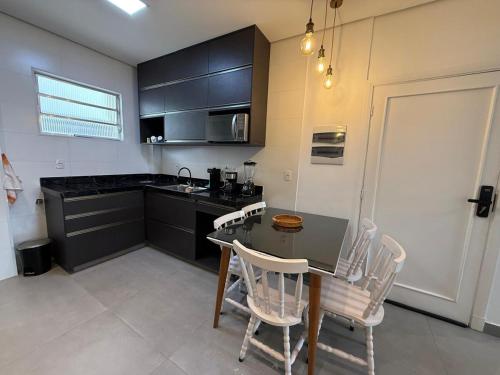 a kitchen with a table and chairs and a counter at Apê pé na areia in Santos