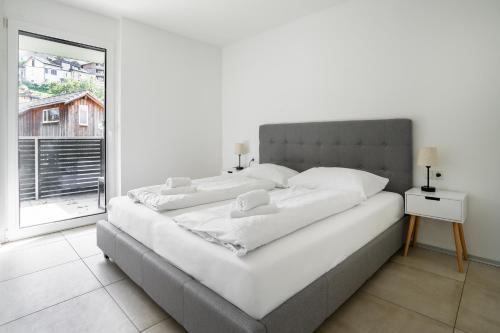 a large bed in a white room with a window at homy City Lodge in Feldkirch, Grenznähe und doch Zentral in Feldkirch