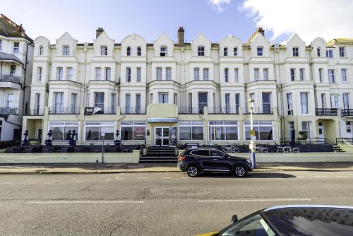 a car parked in front of a large white building at The Majestic Hotel in Eastbourne