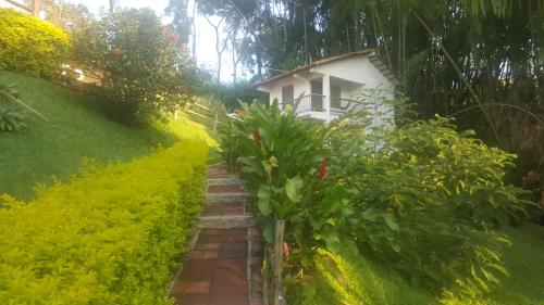 a path leading to a small white house at Finca Hotel Loma Verde in Quimbaya