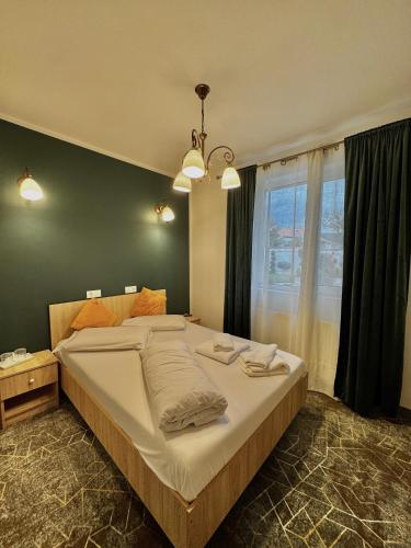 a large bed in a bedroom with a large window at Pensiunea Elis in Pescari
