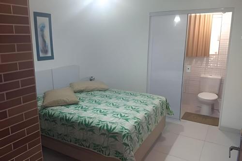 a bedroom with a bed and a bathroom with a toilet at Residencial Flamboyant in Garopaba