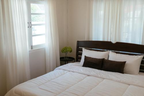 a bedroom with a large white bed with a window at บ้านช่วงเวลาหนึ่ง - House of Moment in Chiang Rai