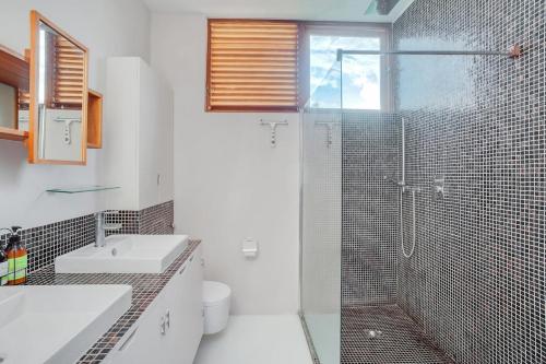 a bathroom with a shower and a sink and a toilet at Pear Tree House Barbados in Saint James