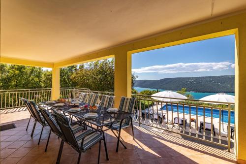 a dining table on a balcony with a view of the water at Seaview Pool House Mytilus - Happy Rentals in Trgetari