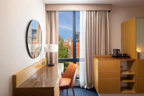 a hotel room with a desk and a window at Hilton Garden Inn Birmingham Brindley Place in Birmingham