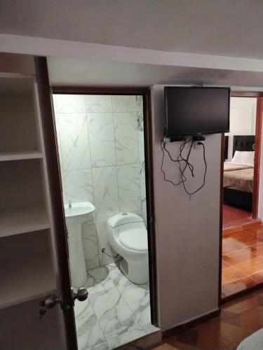 a bathroom with a toilet and a tv on the wall at Hospedaje Apu San Isidro in Urubamba