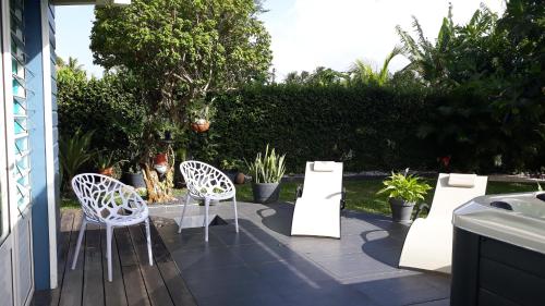 eine Terrasse mit zwei weißen Stühlen und Topfpflanzen in der Unterkunft CAP COULEURS Guadeloupe in Lamentin