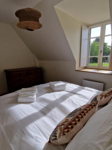 Una cama blanca en una habitación con ventana. en A l'abri des marées - Maison de charme dans le parc du Domaine du Cloitre, en Pléneuf-Val-André