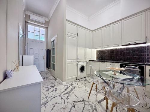 eine Küche mit weißen Schränken und einem Glastisch in der Unterkunft Cris & Ema Luxury Downtown Apartment in Arad