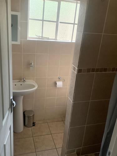 een badkamer met een wastafel en een douche met een raam bij Green Door Cottage 