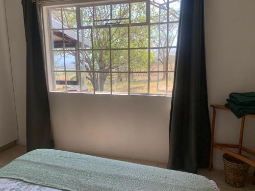 een slaapkamer met een raam en een bed met een sprei bij Green Door Cottage 