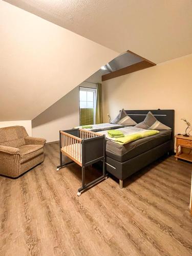 a bedroom with a bed and a chair and a crib at Pension Finkenschenke in Gröditz