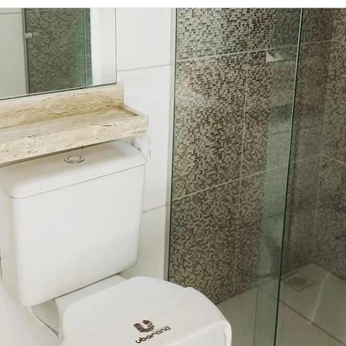 a bathroom with a toilet and a glass shower at Flat Ubarana Maragogi-AL in Maragogi