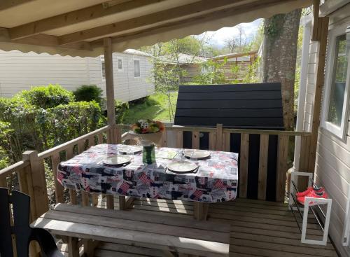 a table on a deck with a table cloth on it at Cosy Mobil-Home climatisé in Aureilhan