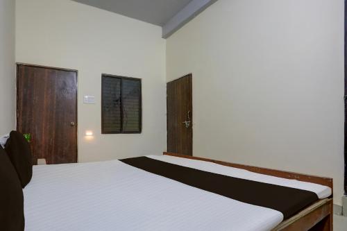 une chambre avec un lit blanc avec une tête de lit en bois dans l'établissement SPOT ON by OYO Hotel Sun City, à Prayagraj