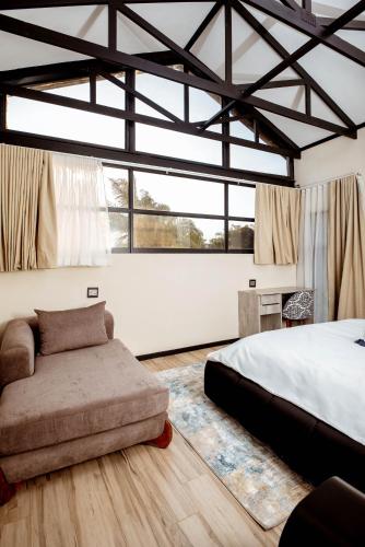 a bedroom with a bed and a couch and windows at The Pinnacle Polokwane in Polokwane