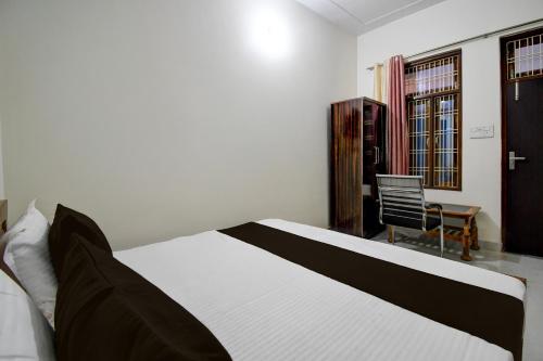 MalhourにあるHotel O Ananta Grandの白と黒のベッドと椅子のある寝室
