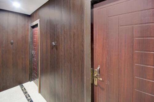 Un pasillo con dos puertas de madera y una puerta roja. en Hotel O Royal Inn Hotel, en Bādshāhnagar